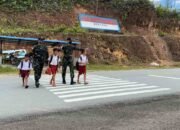 Anggota Satgas Yonif 144/Jy Bantu Anak SDN 05 Lewat  Penyebrangan di Perbatasan