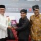 Menyerahkan buku 100 syair religius karangan Prof Usmaan Jakfar saat lounching buku tersebut.