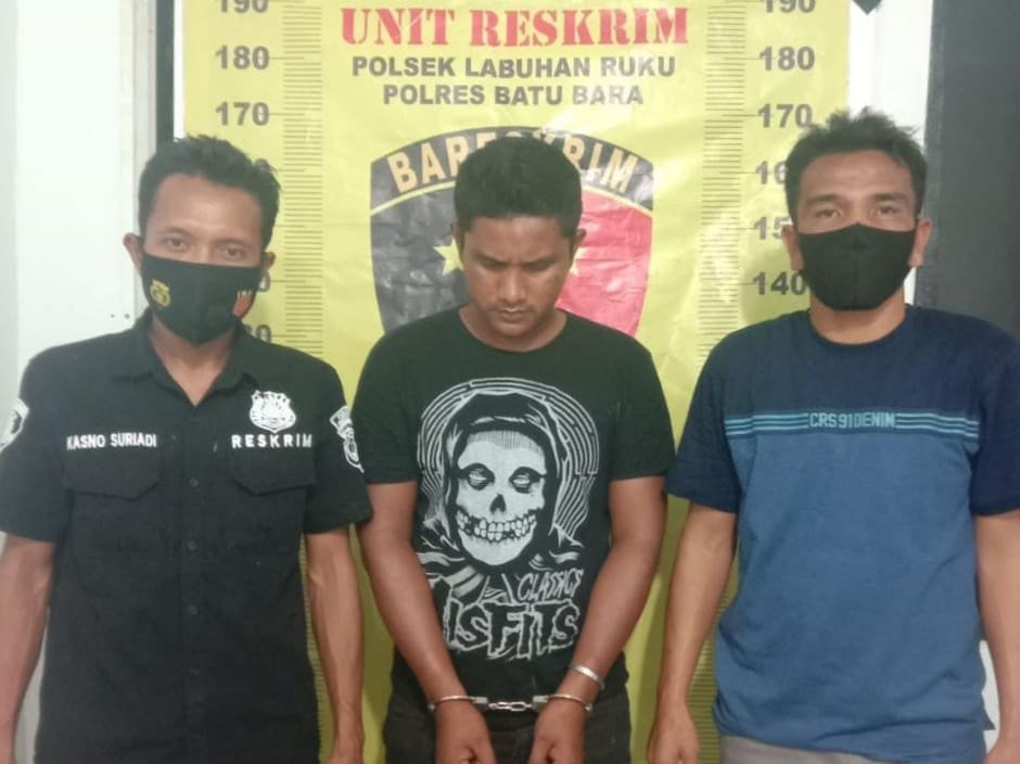 Tersangka Asri di apit petugas, usai menjalani pemeriksaan di Polsek Labuhan Ruku. (Foto: Humas).