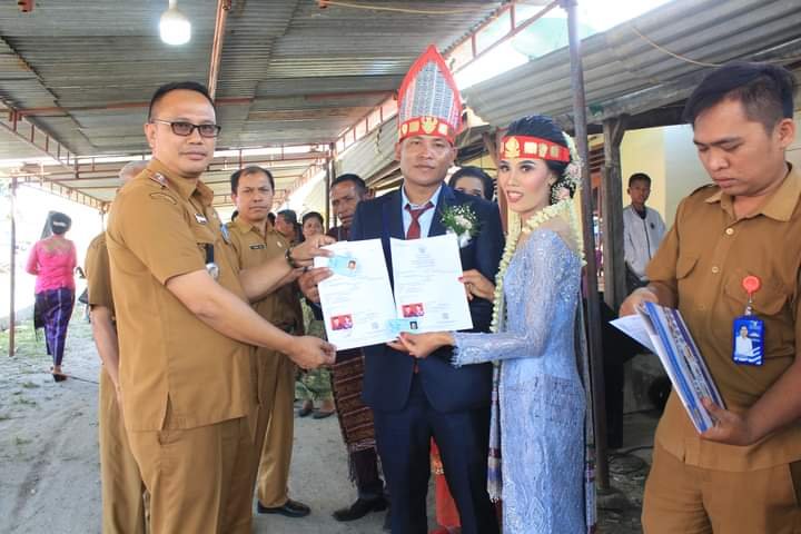 Keterangan foto : Camat Sitinjo Tony Simon Malau (berkacamata hitam) saat menyerahkan akta pernikahan kepada pengantin baru marga Tampubolon di desa Sitinjo, Selasa (16/5/2023). (foto : Sondang).