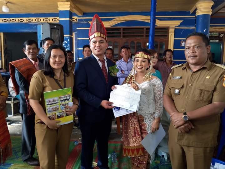 Camat Siempat Nempu, Binuar Malau saat menyerahkan akta pernikahan pengantin baru didesa Jumateguh, Selasa (2/7/2024).(kedanmews.com/Sondang Silalahi).